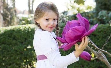 Little girl standing next to giant bright pink magnolia